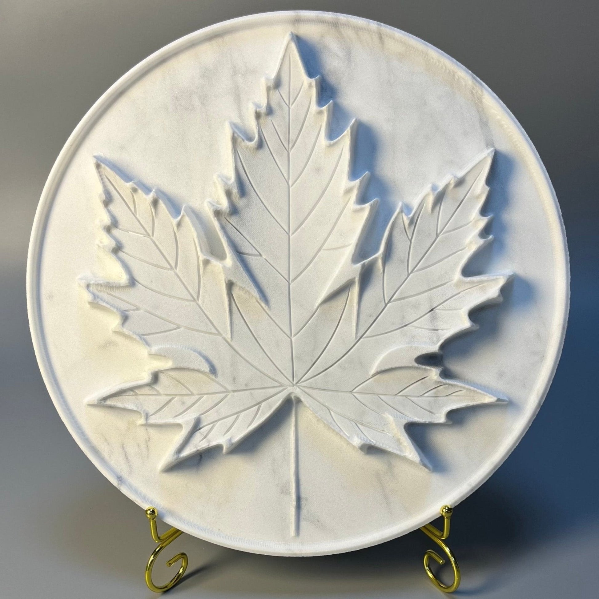 White marble tray with an intricately carved maple leaf design.