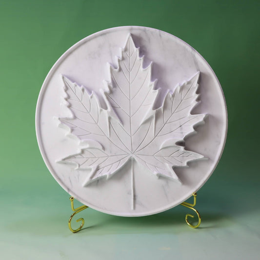 White marble tray with an intricately carved maple leaf design.