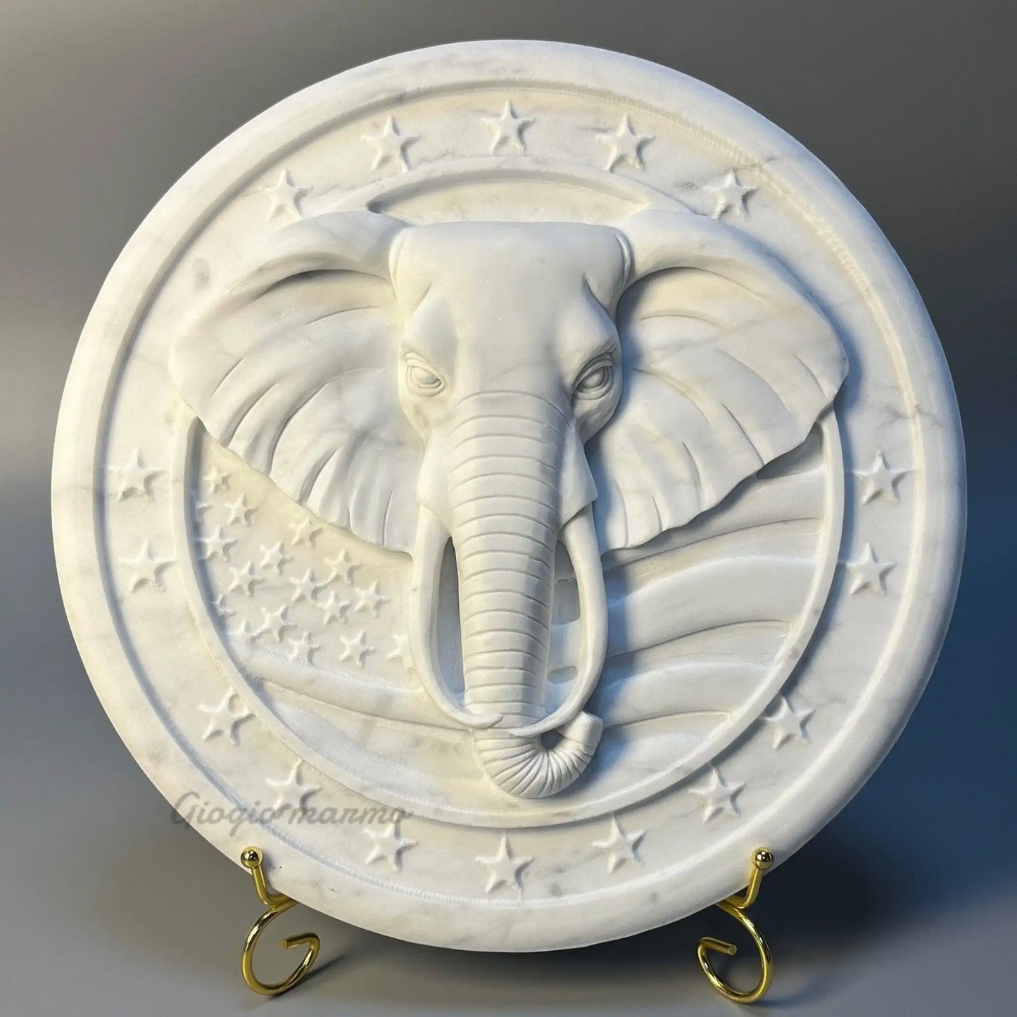 White marble relief sculpture featuring an intricately carved elephant head with star accents.