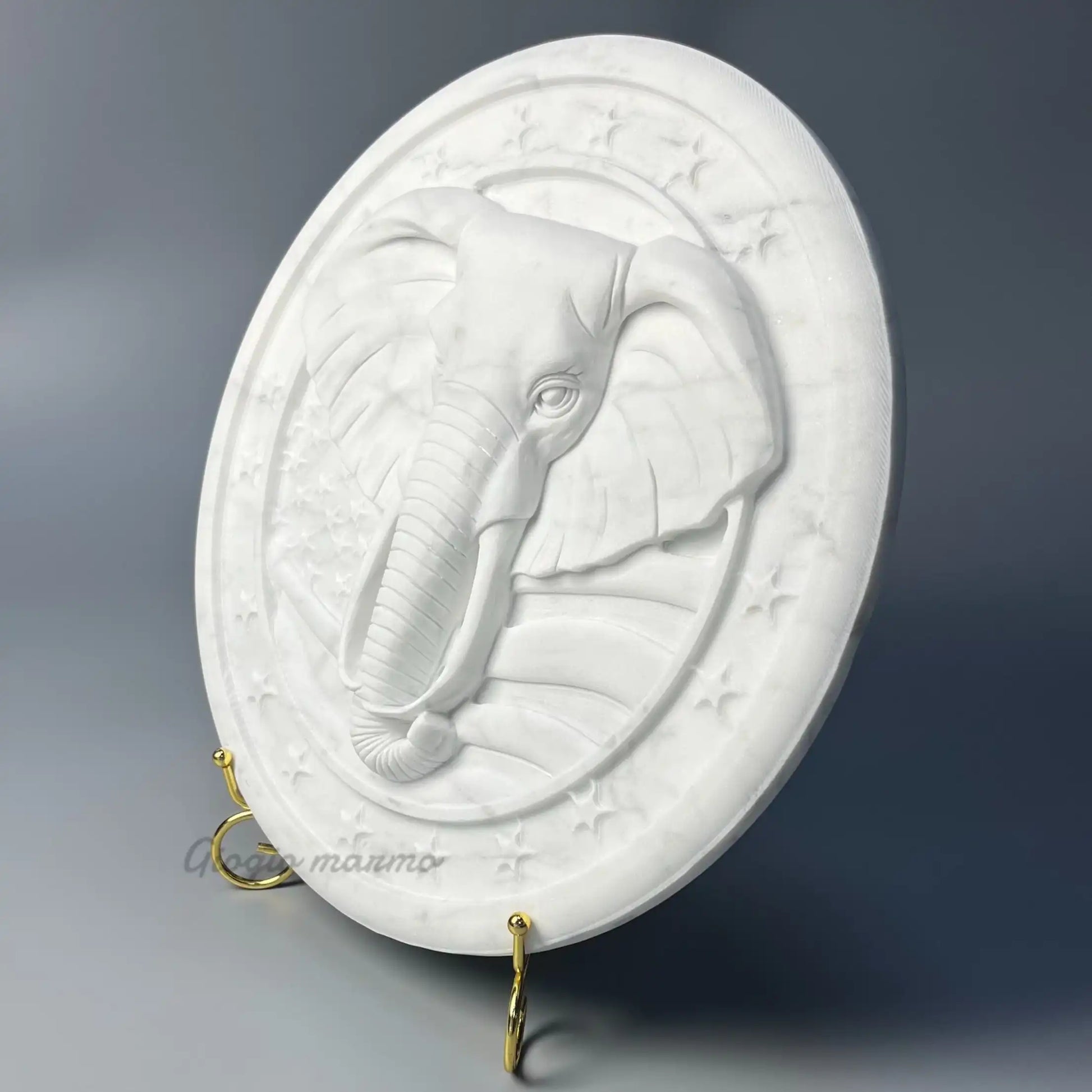 White marble relief sculpture featuring an intricately carved elephant head with star accents.