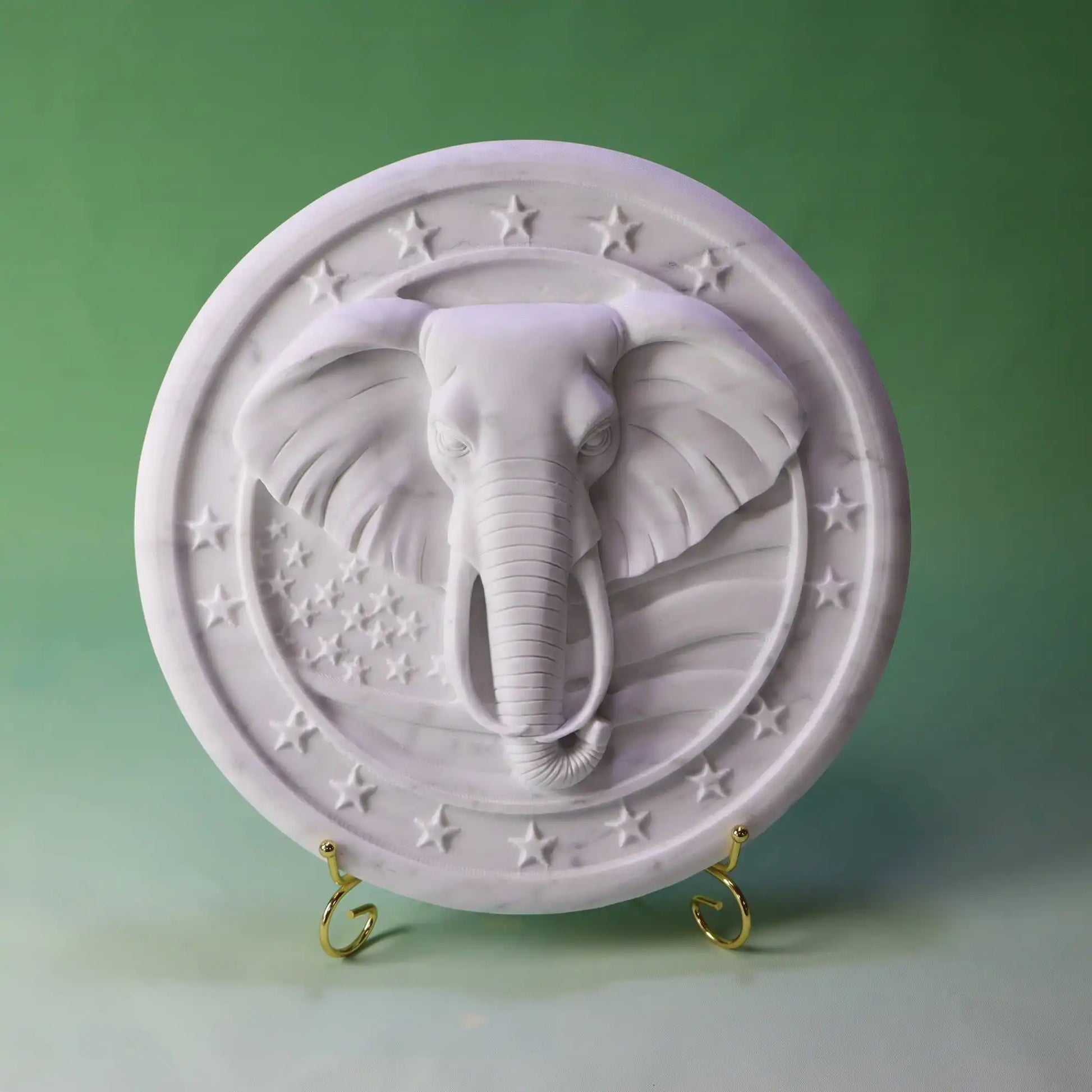 White marble relief sculpture featuring an intricately carved elephant head with star accents.