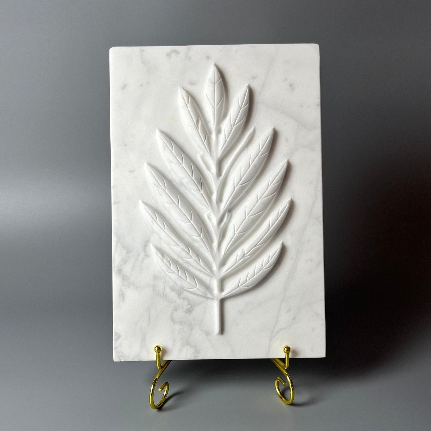 White marble plate with intricately carved olive leaves design, perfect for decorative use.